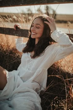 a woman is sitting in the grass and smiling