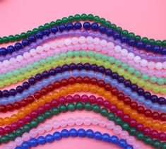 many different colored beads on a pink background