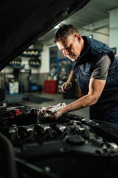 a mechanic working on the hood of a car in a garage with his hands on the engine