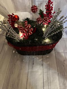 a basket filled with candy canes and christmas decorations on top of a wooden floor