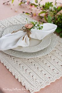 the table is set with white plates and napkins, pink flowers are in the background