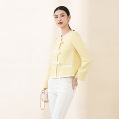 Crafted with a premium light yellow textured fabric reminiscent of the iconic Coco Chanel style, this jacket exudes sophistication and elegance. The subtle shimmer adds a touch of luxury, making it a valuable addition to your wardrobe.Featuring a short boxy silhouette, the jacket offers versatility and comfort. The classic round neckline complements all body types, ensuring a flattering fit without constraints.Adding to its charm, the jacket is designed with a hint of relaxed volume in the silhouette, creating a perfect balance. The contrast trim in beige and delicate bow detail on the shoulders enhance the romantic vibe, while the light-colored interior lining adds a refreshing and vibrant touch. Elegant Tailored Cream Tweed Jacket, Chic Beige Tweed Jacket, Chic Spring Formal Tweed Jacket, Elegant Gold Tweed Jacket For Work, Chic Spring Tweed Jacket For Formal Occasions, Elegant Cream Tweed Jacket, Elegant Spring Evening Tweed Jacket, Chic Cream Tweed Jacket For Formal Occasions, Elegant Gold Blazer For Spring