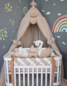 a baby crib with two stuffed animals in it and a rainbow painted wall behind the crib