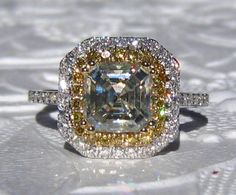 a fancy ring with an assorted diamond surrounded by yellow and white diamonds in the center