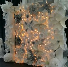 an artificial flower wall with lights in the middle and white flowers on it's sides