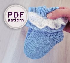 a hand holding a blue knitted mitt with white crochet on it