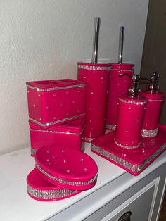 pink bathroom accessories on top of a dresser