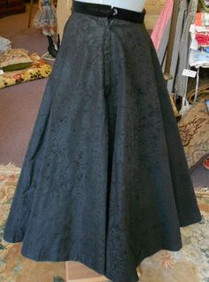 "1950's, 26\", black flocked taffeta circle skirt, with a black velvet waist band, with a black net under petticoat. Skirt is fastened on left side with a zipper and black button atop zipper. Label reads \"Rosecrests\" NY. Measurements: waist 26\" waist to hem 31\" width at bottom 128\" of skirt Condition: excellent" Victorian Style Fitted Full Skirt, Black Full Skirt Crinoline Petticoat, Black Crinoline Full Skirt Petticoat, Elegant Black Skirt For Costume, Vintage Gathered Skirt For Costume, Vintage Costume Gathered Skirt, Costume Full Gathered Skirt, Costume Full Skirt With Gathered Details, Fitted Black Long Petticoat