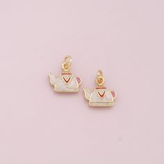 two gold - plated teapot charms with hearts on them