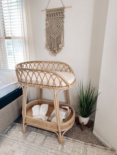 a wicker baby crib in a bedroom next to a bed with a potted plant