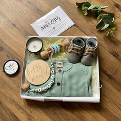 an open box containing baby's clothes, shoes and personalized items on a wooden table