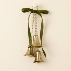 two bells hanging from a green ribbon on a wall