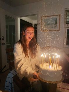 a woman sitting in front of a cake with lit candles