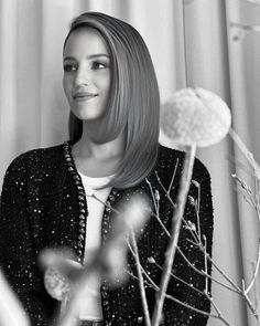 a black and white photo of a woman in front of a window with dandelions