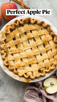 an apple pie sitting on top of a white plate next to apples and cinnamon sticks