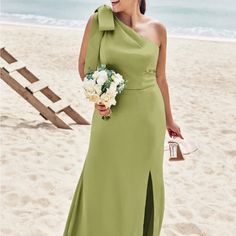 a woman is standing on the beach in a green dress and holding a flower bouquet