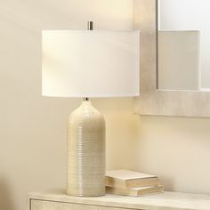 a white lamp sitting on top of a table next to a mirror and a dresser