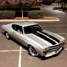 an old muscle car is parked in a parking lot with its hood painted black and silver