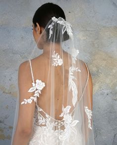 the back of a woman wearing a veil with flowers on it and pearls in her hair