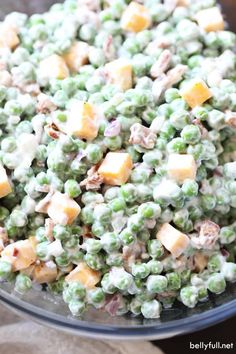 a bowl filled with peas and cheese on top of a table