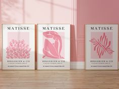 three framed art prints in pink and white on a wooden floor next to a pink wall