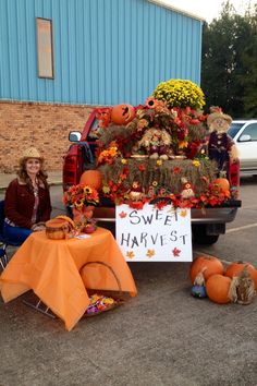 a woman sitting in front of a truck decorated with pumpkins and hay