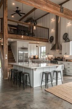 a large kitchen with an island and bar stools in the center, surrounded by wooden beams