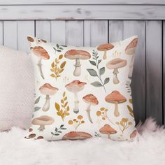 a pillow with mushrooms and leaves on it sitting on a white furnishing next to a wooden headboard