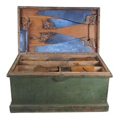 an old wooden box with several different types of knives in it and the lid opened