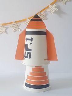 an orange and white paper rocket on a string