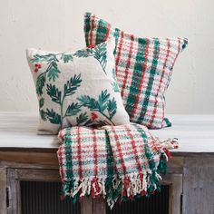 three christmas pillows sitting on top of a wooden table next to a window sill