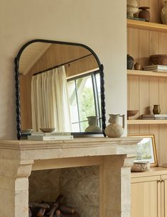 a fireplace in a living room with a mirror on it's mantle and shelves