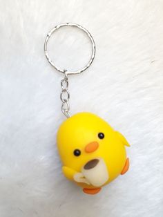 a yellow rubber ducky keychain is on a white fur covered surface with a metal ring