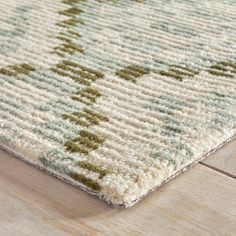 a close up of a rug on the floor with wood and tile in the background