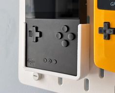 two video game controllers mounted to the side of a white and yellow wall hanging on a wall