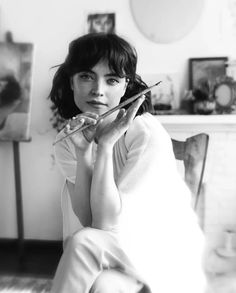 a black and white photo of a woman sitting on the floor with scissors in her hand