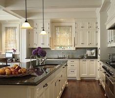 a kitchen filled with lots of white cabinets and counter top next to a stove top oven