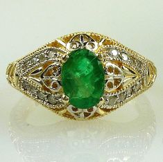 ALL OUR JEWELRY IS HANDCRAFTED IN THE USA ALL OUR GEMSTONES ARE NATURAL NOT LAB CREATED Such a lovely, delicate filigree Emerald ring, and encrusted with 16 Diamonds. This genuine Colombian Emerald is of exceptional color and clarity is just beautiful. The beading and filigree in the gold mounting encircle nearly the entire ring!  It would make an exquisite engagement or May birthstone ring!  Set in solid 14k yellow gold.  You will absolutely ADORE this ring!! One 8x6 oval Emerald, 1.50 carats S Fine Jewelry Yellow Gold Emerald Ring With Intricate Design, Fine Jewelry Emerald Ring With Intricate Design, Gold Emerald Ring With Intricate Design, Oval Shape, Oval Gold Emerald Ring With Intricate Design, Yellow Gold Emerald Ring With Intricate Design, Elegant Yellow Gold Emerald Ring With Intricate Design, Fine Jewelry Emerald Ring With Intricate Design For Wedding, Wedding Emerald Ring With Intricate Design, 14k Gold Green Rings With Intricate Design