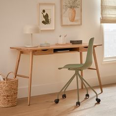 a desk with a chair, lamp and pictures on the wall in front of it