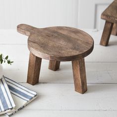 a wooden stool sitting on top of a white floor next to a vase filled with flowers