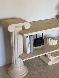 a book shelf made out of concrete with books on it and a handbag next to it