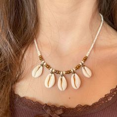 a woman wearing a necklace with seashells on it