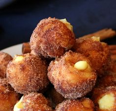 a pile of doughnuts sitting on top of a white plate next to cinnamon sticks