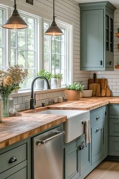 a kitchen with green cabinets and wooden counter tops, two hanging lights over the sink