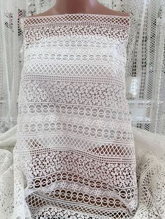 a white crocheted top on a mannequin with sheer curtains in the background