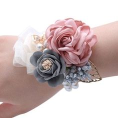 a woman's arm wearing a bracelet with flowers and pearls on the clasps