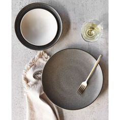 a table setting with plates, silverware and napkins on it next to a glass of wine