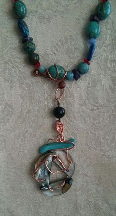 This is a 4 strand glass,stone, and metal beaded statement necklace. It is comprised of glass and stone (carnelian,agate,coral, dyed howlite, turquoise, jasper, lapis, shattuckite, abalone) beads in shades of red and blue, copper wire, silvertone jump rings, and a silvertone lobster claw clasp. The necklace is strung on nylon coated steel wire.Shortest strand = 19" Longest strand = 30" Focal = 4.25" Bohemian Jasper Wire Wrapped Necklaces, Turquoise Agate Wire Wrapped Necklaces, Turquoise Agate Wire Wrapped Necklace, Handmade Turquoise Agate Necklace For Healing, Wire Wrapped Necklaces With Round Beads, Artisan Handmade Chrysocolla Beaded Necklaces, Handmade Chrysocolla Beaded Necklaces As Gift, Unique Turquoise Necklace With Round Beads, Unique Wire Wrapped Necklaces With Round Beads