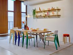 a dining room table with chairs and shelves on the wall