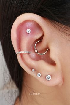 a woman with three piercings on her ear and behind the ear is a diamond ring